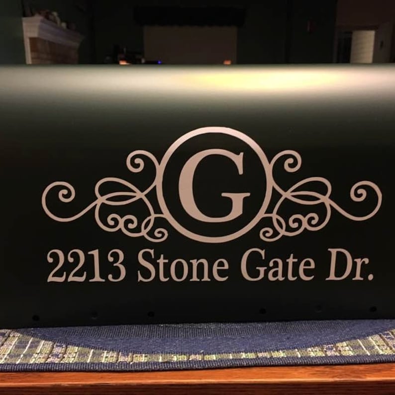 May include: A green mailbox with a white vinyl decal. The decal features a decorative scroll design with the letter "G" in a circle and the address "2213 Stone Gate Dr."