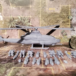 May include: A gray plastic model of an attack helicopter with a set of gray plastic missiles. The helicopter is about 4 inches long and the missiles are about 1 inch long. The helicopter is sitting on a gray surface with a US quarter for scale.