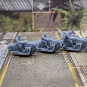 May include: Three gray miniature motorcycles with riders. Each motorcycle has a unique design with multiple exhaust pipes. The riders are wearing helmets and are in a riding position.