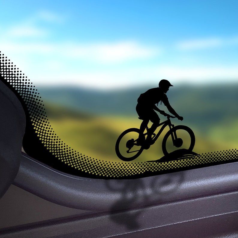 May include: Silhouette of a person riding a mountain bike on a blurred background of a landscape with a blue sky.