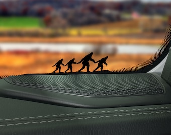 Puede incluir: Un interior de coche negro con una rejilla de altavoz negra. Cuatro figuras de silueta negra de Bigfoot caminan por la rejilla, cogidos de la mano.