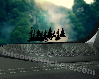 May include: Black and white silhouette of a tent, campfire, and trees on a car window. The sticker is on a black speaker grill. *Jeep not include*