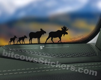 May include: A black silhouette decal of a family of moose walking in a line. The decal is 5 inches wide and is shown on a car window.