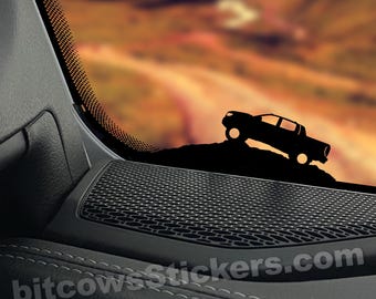 May include: A black silhouette of a pickup truck driving up a hill, with a sunset background. The truck is on a car window with a black speaker grill below it. The text "bitcowsStickers.com" is visible in the bottom right corner.