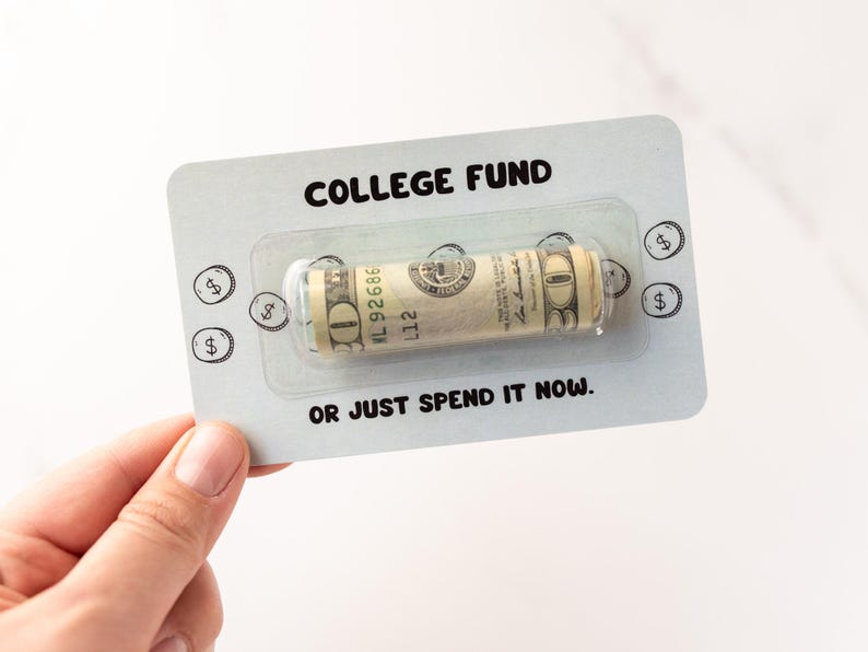 Może przedstawiać: Prostokątna jasnoszara karta z napisem COLLEGE FUND u g&oacute;ry i OR JUST SPEND IT NOW u dołu. Przezroczyste plastikowe opakowanie typu blister pośrodku zawiera zwinięty banknot dwudziestodolarowy. Małe ilustracje monet otaczają środkową część karty.