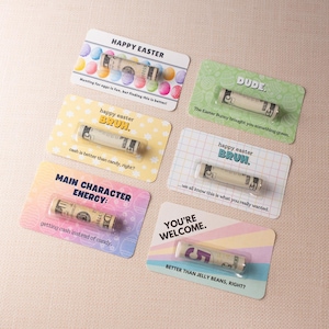 May include: Five colorful cards with Easter-themed messages and rolled-up dollar bills inside. The cards have messages like "Happy Easter", "Dude", "Happy Easter, Bruh", "Main Character Energy", and "You're Welcome".