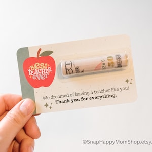 May include: A red apple with the words "Best Teacher Ever" on it. A rolled up bill of money is attached to the card. The card says "We dreamed of having a teacher like you! Thank you for everything."