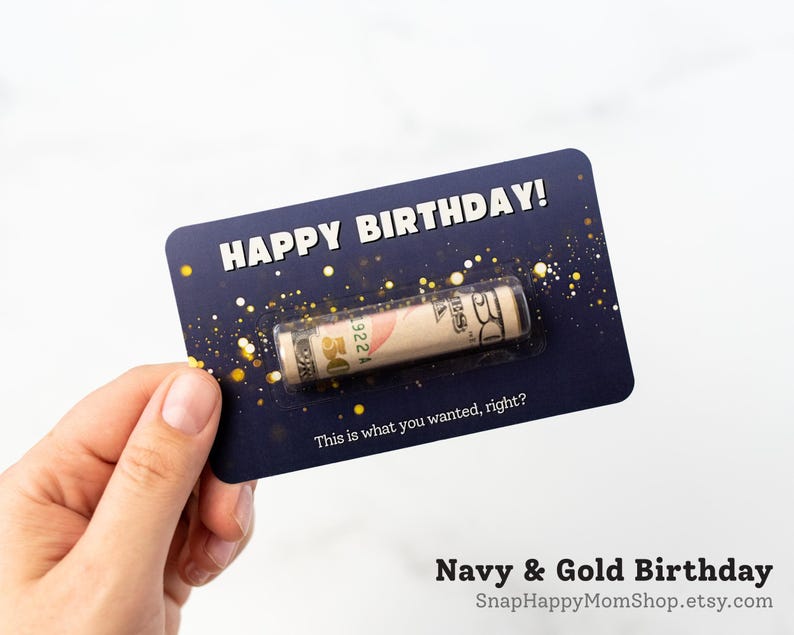 Może przedstawiać: Prostokątna granatowa kartka urodzinowa ze złotymi akcentami brokatu oraz napisem HAPPY BIRTHDAY! i This is what you wanted, right? Przezroczyste plastikowe opakowanie typu blister zawiera zwinięty banknot pięćdziesięciodolarowy.