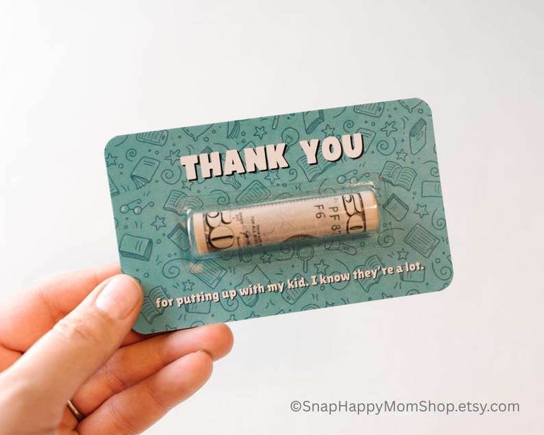 May include: A teal card with a white border and a rolled up dollar bill inside a clear plastic window. The card has a pattern of books and stars and says "THANK YOU" in white letters. The text below the window says "for putting up with my kid. I know they're a lot."