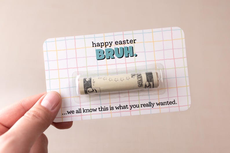 May include: A white card with a grid pattern and the text "happy easter BRUH."  A rolled up dollar bill is inside a clear plastic sleeve on the card. The text "...we all know this is what you really wanted." is at the bottom of the card.
