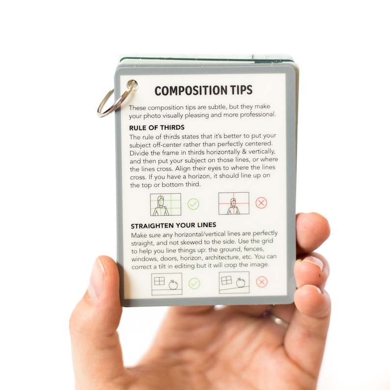 May include: A white card with the title "Composition Tips" and text explaining the rule of thirds and how to straighten lines in photography. The card has a green border and a silver ring.