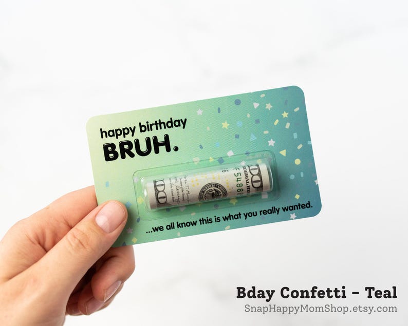 Może przedstawiać: Prostokątna kartka urodzinowa w kolorze morskim z wzorem w konfetti oraz napisem "happy birthday BRUH." i "...we all know this is what you really wanted." Przezroczyste plastikowe opakowanie typu blister zawiera zwinięty banknot studolarowy.