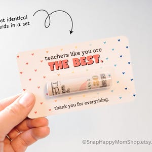 May include: A white card with a pink heart pattern and the text "teachers like you are THE BEST. thank you for everything."  A rolled up bill is tucked into the card.