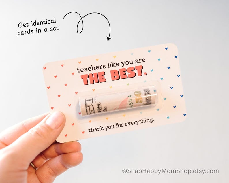 May include: A white card with a pink heart pattern and the text "teachers like you are THE BEST. thank you for everything."  A rolled up bill is tucked into the card.