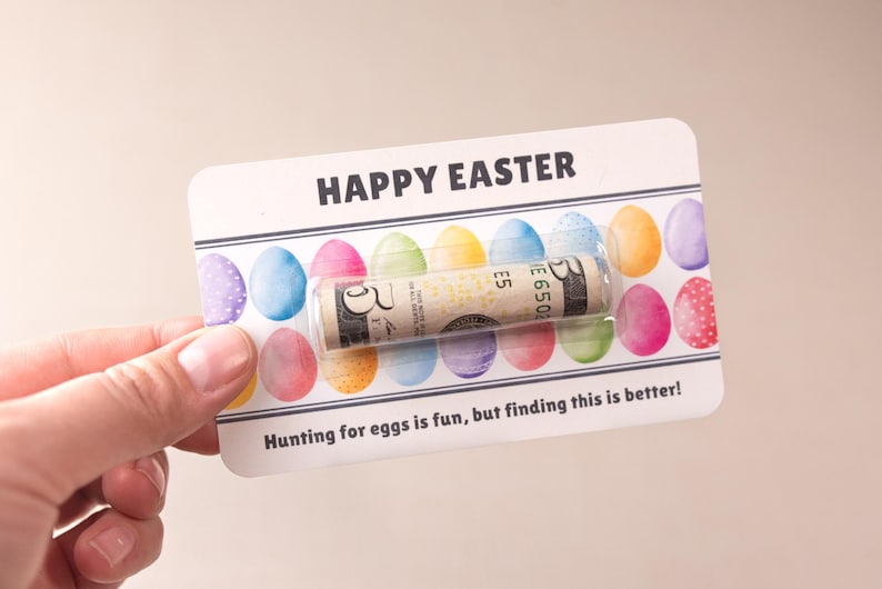 May include: A white card with the words "HAPPY EASTER" printed in black. The card has a row of colorful Easter eggs printed on it. A rolled up dollar bill is tucked inside the card.