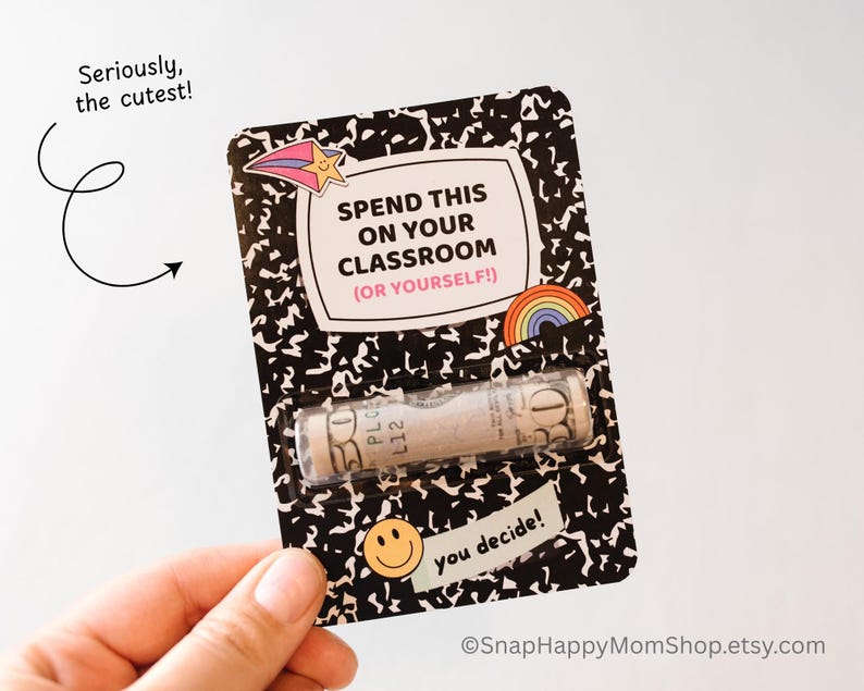 May include: A black and white notebook-style card with the text "Spend this on your classroom (or yourself!)" and a rolled-up dollar bill inside. The card has a rainbow sticker and a smiley face sticker.