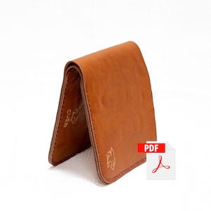 Puede incluir: Una cartera de cuero marrón con un diseño de solapa. La cartera tiene un logotipo dorado en relieve en la parte delantera y trasera. El logotipo es una cabeza de animal estilizada. La cartera está doblada por la mitad y está sobre una superficie blanca.