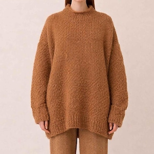 Op de afbeelding: Een grofgebreide trui in een warme camelbruine kleur met een hoge col, lange mouwen met geribbelde boorden en een ruime pasvorm, gecombineerd met een bijpassende, recht gesneden gebreide broek van hetzelfde gestructureerde garen.