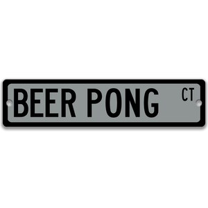 以下が含まれることがあります： 「BEER PONG CT」と黒文字で書かれた銀色の金属製の看板です。