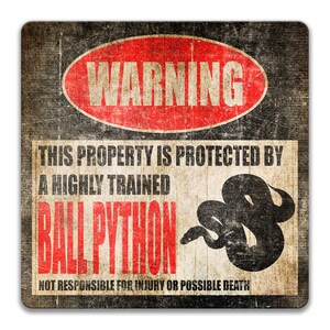 May include: A warning sign with a distressed, vintage look. It reads "WARNING" in a red oval with black text. The sign says "This property is protected by a highly trained Ball Python. Not responsible for injury or possible death." A black and white image of a ball python is in the centre of the sign.