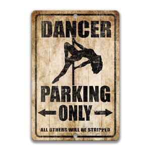 May include: A vintage-style metal sign with a distressed background. It features a silhouette of a woman on a pole dance pole with the text "Dancer Parking Only" and the smaller text "All others will be stripped".