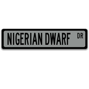 May include: A gray street sign with black lettering that reads "NIGERIAN DWARF DR".