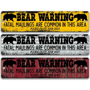 Peut inclure: Trois panneaux métalliques rustiques avec une silhouette d'ours noir et le texte "BEAR WARNING FATAL MAULINGS ARE COMMON IN THIS AREA PLEASE ENJOY YOUR VISIT". Les panneaux sont jaunes, gris et rouges.