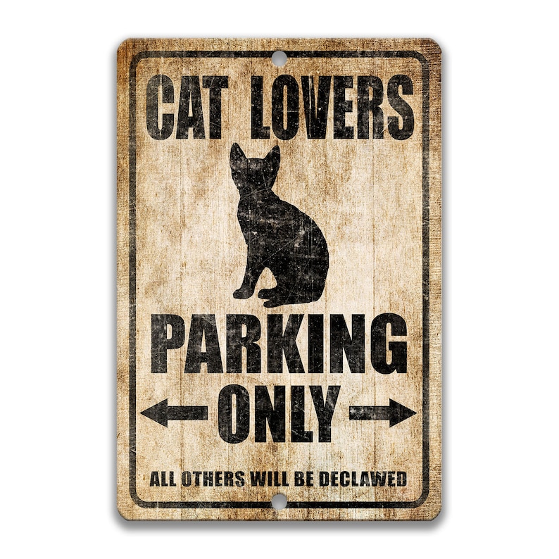 Pu&ograve; includere: Un cartello in metallo in stile vintage con uno sfondo marrone invecchiato. Il cartello recita "Cat Lovers Parking Only" con una silhouette nera di un gatto seduto al centro. Il testo "All others will be declawed" &egrave; stampato sotto il gatto.