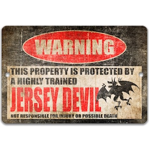 Puede incluir: Un cartel de advertencia con un aspecto desgastado y vintage. Presenta un círculo rojo con la palabra "WARNING" en texto blanco. El cartel dice "This property is protected by a highly trained Jersey Devil. Not responsible for injury or possible death." Una silueta negra de un diablo con alas se muestra en la esquina inferior derecha.