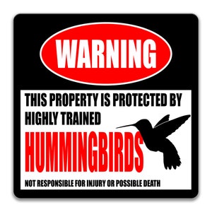 Puede incluir: Un cartel en blanco y negro con un cartel de advertencia rojo que dice "WARNING" en letras blancas. El cartel dice "This property is protected by highly trained hummingbirds. Not responsible for injury or possible death." Se muestra una silueta negra de un colibr&iacute; en el cartel.