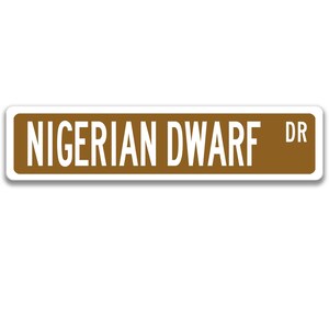 May include: A brown street sign with white text that reads "NIGERIAN DWARF DR".