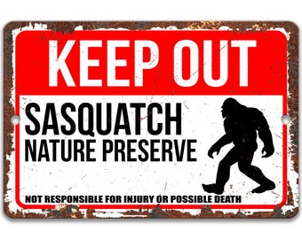 May include: A rusty metal sign with a red background and white text that reads "KEEP OUT SASQUATCH NATURE PRESERVE NOT RESPONSIBLE FOR INJURY OR POSSIBLE DEATH". A black silhouette of a sasquatch is walking to the right.
