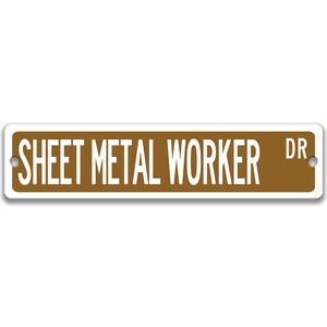 May include: A rectangular street sign with the words "SHEET METAL WORKER DR" in white capital letters on a brown background. The sign has rounded corners and two holes for mounting.