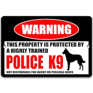 May include: Black and white rectangular sign with the word "WARNING" in a red oval. The sign reads "THIS PROPERTY IS PROTECTED BY A HIGHLY TRAINED POLICE K9" with a silhouette of a dog. The bottom of the sign reads "NOT RESPONSIBLE FOR INJURY OR POSSIBLE DEATH."