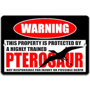 May include: Black rectangular sign with the word "WARNING" in a red oval. The sign reads "THIS PROPERTY IS PROTECTED BY A HIGHLY TRAINED PTEROSAUR" in white and red text, with a black pterosaur silhouette. The bottom text reads "NOT RESPONSIBLE FOR INJURY OR POSSIBLE DEATH."