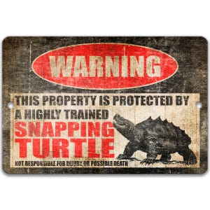 Pode incluir: Uma placa de metal retangular com um acabamento desgastado. A placa apresenta um oval vermelho com a palavra "WARNING" em branco. Abaixo, o texto diz "THIS PROPERTY IS PROTECTED BY A HIGHLY TRAINED SNAPPING TURTLE". Um gráfico de uma tartaruga está à direita.