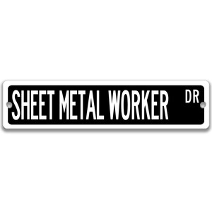 May include: A rectangular black and white sign with the text "SHEET METAL WORKER DR" in bold, white capital letters. The sign has rounded corners and two holes for mounting.