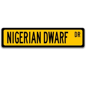 May include: A yellow road sign with black text and a black border. The sign reads "NIGERIAN DWARF DR".