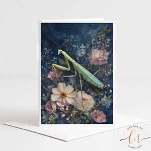 Puede incluir: Tarjeta de felicitación blanca con una ilustración detallada de una mantis religiosa rodeada de flores blancas, rosas y azules sobre un fondo azul oscuro. El texto "DESIGNS BY LINDA NEE" está en la esquina inferior derecha.