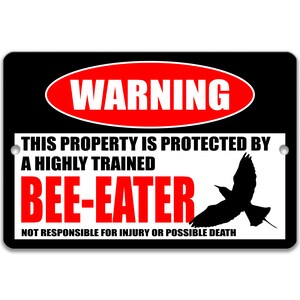 Può includere: Un cartello di avvertimento nero e rosso con testo bianco che dice "WARNING THIS PROPERTY IS PROTECTED BY A HIGHLY TRAINED BEE-EATER NOT RESPONSIBLE FOR INJURY OR POSSIBLE DEATH". Una silhouette nera di un uccello che vola verso destra.