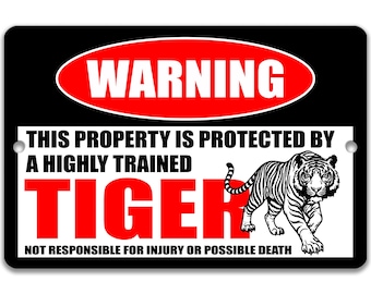 May include: Black rectangular sign with a red oval that says "WARNING". Below, the sign reads "THIS PROPERTY IS PROTECTED BY A HIGHLY TRAINED TIGER" in white and red text. A black and white tiger illustration is on the right.