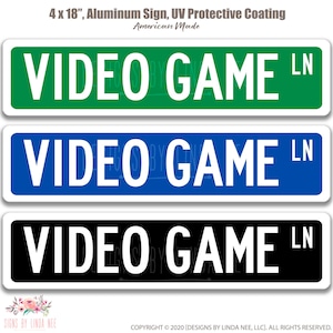 May include: Three rectangular aluminum signs, each 4 x 18 inches, with the text "VIDEO GAME LN" in white. The top sign is green, the middle is blue, and the bottom is black. The signs have a UV protective coating and are American made.