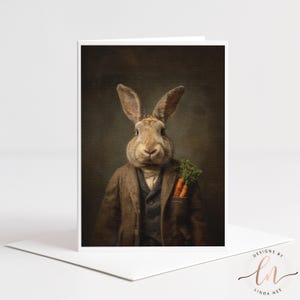 May include: Greeting card featuring a rabbit dressed in a tweed suit, waistcoat, and shirt, with carrots in its pocket. The rabbit has a serious expression against a dark background. The card is white with the text "DESIGNS BY LINDA NEE" in the bottom right corner.