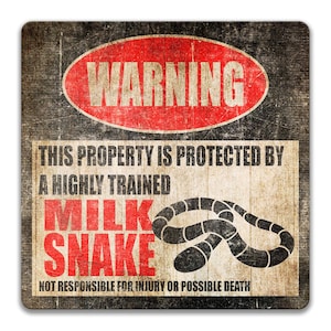 May include: A warning sign with a red circle and the word "WARNING" in white letters. The sign reads "This property is protected by a highly trained milk snake. Not responsible for injury or possible death." The sign has a distressed, vintage look.