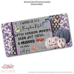 Könnte beinhalten: Ein Halloween-Metall-Schild mit einem violetten und schwarzen Muster an der Kante. Das Schild hat einen grauen Hintergrund mit weißem Text, der lautet: "I wanna go to a Pumpkin Patch, watch horror movies, drink hot cocoa, & murder someone. You know, fall shit."