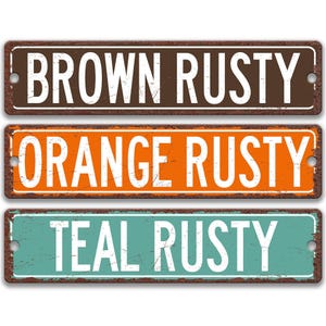 three weathered metal street signs with the names of different colors: brown, orange, and teal.