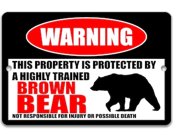 May include: A black and white warning sign with red text that reads "WARNING". The sign says "This property is protected by a highly trained BROWN BEAR. Not responsible for injury or possible death." A silhouette of a brown bear is shown on the sign.