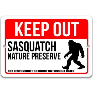 Op de afbeelding: Een wit bord met rode letters met de tekst "KEEP OUT" en "SASQUATCH NATURE PRESERVE". Een zwart silhouet van een sasquatch loopt naar rechts. Onderaan het bord staat "NOT RESPONSIBLE FOR INJURY OR POSSIBLE DEATH."
