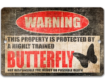 May include: A black and white warning sign with red text that reads "WARNING THIS PROPERTY IS PROTECTED BY A HIGHLY TRAINED BUTTERFLY NOT RESPONSIBLE FOR INJURY OR POSSIBLE DEATH". The sign has a distressed, vintage look and features a black silhouette of a butterfly.