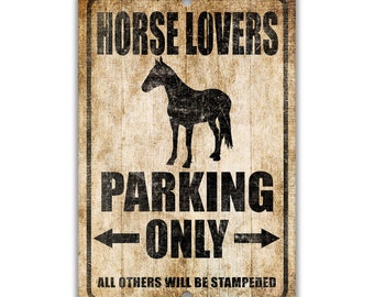 May include: A rustic brown metal sign with the text "Horse Lovers Parking Only" in black. A silhouette of a horse is in the centre of the sign. The text "All others will be stampeded" is at the bottom of the sign.